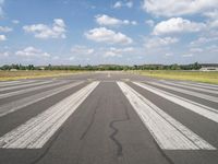 a large airport has many lines in the ground, but few of people are riding bikes down the runway