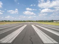 a large airport has many lines in the ground, but few of people are riding bikes down the runway