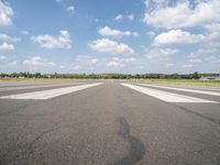 a large airport has many lines in the ground, but few of people are riding bikes down the runway