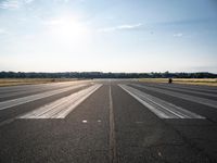 a runway that has been painted white and black, with the sun shining on top