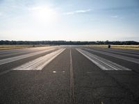 a runway that has been painted white and black, with the sun shining on top