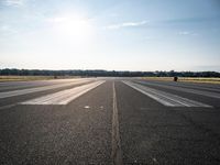 a runway that has been painted white and black, with the sun shining on top