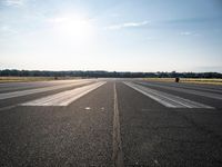 a runway that has been painted white and black, with the sun shining on top