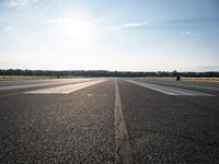 a runway that has been painted white and black, with the sun shining on top