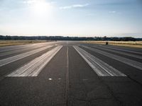 a runway that has been painted white and black, with the sun shining on top