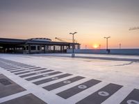 a white and blue walkway leading to a terminal with planes at dusk, with one person on top