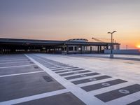 a white and blue walkway leading to a terminal with planes at dusk, with one person on top