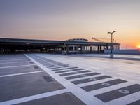 a white and blue walkway leading to a terminal with planes at dusk, with one person on top