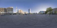 a round lens image of a city with tall buildings in the background and people sitting on benches