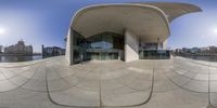 a fish eye lens shot of an architectural building in a city, including a boat