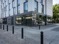 a few poles on the sidewalk by a building with a parking sign in front of it