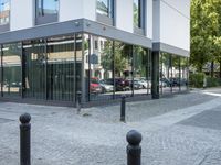 a few poles on the sidewalk by a building with a parking sign in front of it