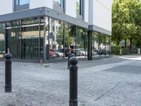 a few poles on the sidewalk by a building with a parking sign in front of it