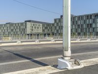 a crosswalk in front of a huge building near a highway with cars parked on the side of it