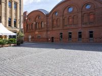 an old bricked building with large windows and arches on it is standing in the center of this square