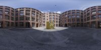 a big brick building with several buildings behind it as a fisheye lens shot taken from inside