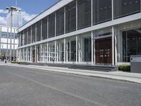 a building with a street and sidewalk outside of it with windows and a lot of grass