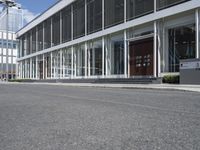 a building with a street and sidewalk outside of it with windows and a lot of grass