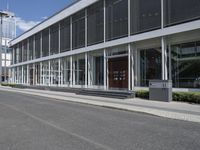 a building with a street and sidewalk outside of it with windows and a lot of grass