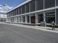 a building with a street and sidewalk outside of it with windows and a lot of grass