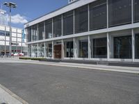 a building with a street and sidewalk outside of it with windows and a lot of grass