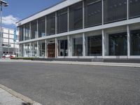 a building with a street and sidewalk outside of it with windows and a lot of grass