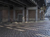 a brick walkway in front of buildings with graffiti on it and two benches at the curb