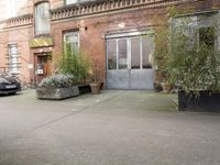 a large planter on the sidewalk outside of a building with a big open door