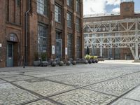 a brick sidewalk with old building and stone planters on either side of it outside