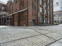 a brick sidewalk with old building and stone planters on either side of it outside