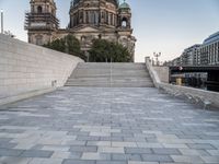 a bench sits in the middle of a brick plaza in front of a cathedral and its steps