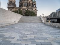 a bench sits in the middle of a brick plaza in front of a cathedral and its steps