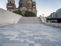 a bench sits in the middle of a brick plaza in front of a cathedral and its steps