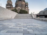 a bench sits in the middle of a brick plaza in front of a cathedral and its steps