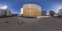 a large circular structure stands in a courtyard surrounded by buildings and other residential architecture, with a wooden fence