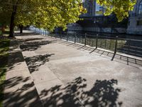 a bridge spans over the river next to a row of buildings and some trees on the sidewalk