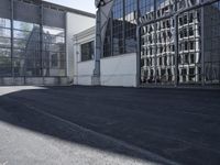 the building is next to the large glass windows in the middle of the area is an empty parking lot