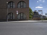 a sign that reads no parking is shown on the side of the road next to a red brick building