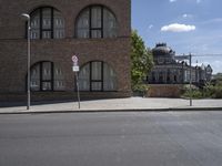 a sign that reads no parking is shown on the side of the road next to a red brick building