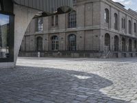 there is an empty public space in this large building, with a clock tower next to the sidewalk