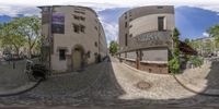 360 panoramic view of people walking on cobble stone street lined with houses