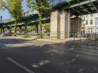 a bicycle is parked under the bridge and a person riding a bike in the street