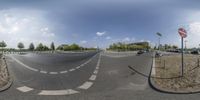 a view looking at a street with some trees and clouds in the sky and trees