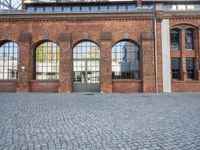 a stone courtyard with large windows and brick walls and a white brick wall behind it