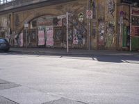 a person walking across a street past some buildings with graffiti on them's walls