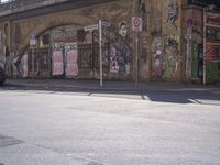 a person walking across a street past some buildings with graffiti on them's walls