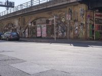 a person walking across a street past some buildings with graffiti on them's walls