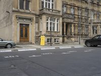 an empty building with signs on the street and people on bikes in traffic passing by