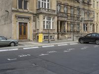 an empty building with signs on the street and people on bikes in traffic passing by