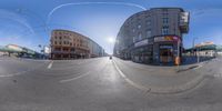 a fish eye view of an empty street with the light on, and buildings in the background